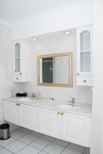 a white bathroom with two sinks and a mirror at Bell Rosen Guest House in Bellville