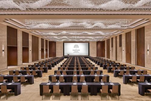 a large room with tables and chairs and a screen at Raffles Shenzhen, Situated in the heart of One Shenzhen Bay, Book Now to Enjoy Free Minibar and Happy Hour Privileges at Long Bar on 71F in Shenzhen