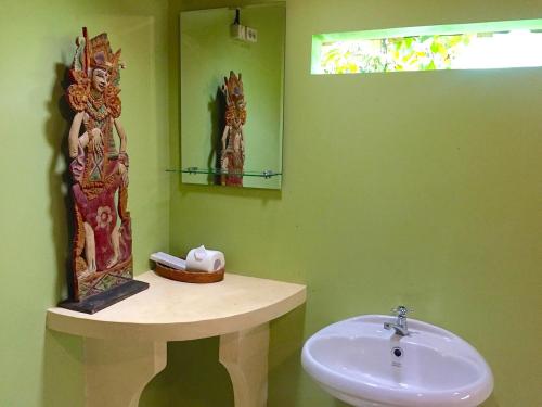 a green bathroom with a sink and a mirror at Bali Mountain Retreat in Selemadeg