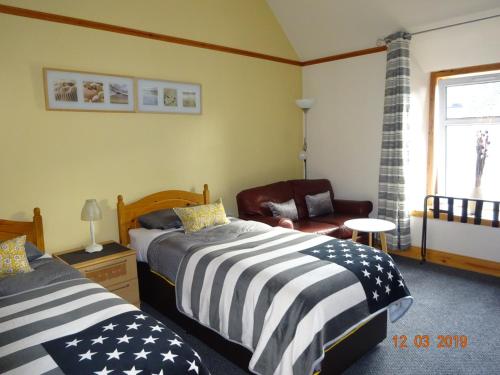 a bedroom with two beds and a chair at Kindale House in Helmsdale