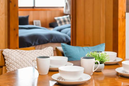 a wooden table with white cups and saucers on it at Condominium Hotel Mihama Upi in Chatan