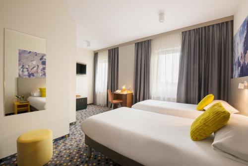 a hotel room with two beds and a table at ibis Styles Warszawa West in Mory