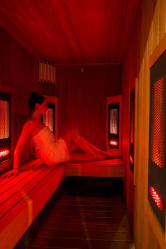 a woman sitting on a bed in a red room at ibis Styles Warszawa West in Mory
