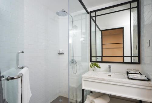 a white bathroom with a sink and a mirror at de Braga, ARTOTEL Curated in Bandung