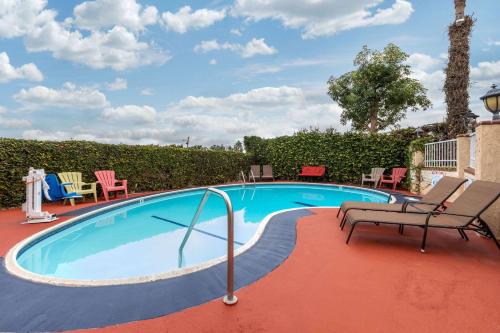 a swimming pool with two chairs and chairs around it at Quality Inn Lomita-Los Angeles South Bay in Lomita