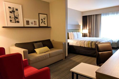 Habitación de hotel con cama, sofá y silla en Comfort Inn & Suites en Slidell