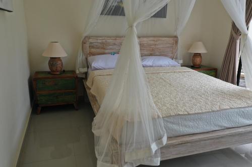 a bedroom with a bed with a mosquito net at Villa Viking in Jimbaran