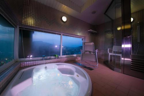 a bath tub in a bathroom with a large window at Hotel Concerto Nagasaki in Nagasaki