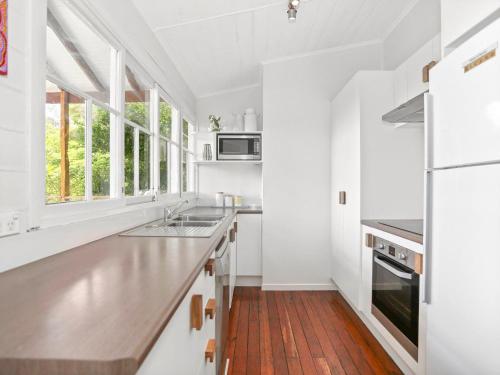 a kitchen with white walls and a wooden floor at Beluso in Byron Bay