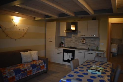 cocina y sala de estar con mesa y sofá en Mimosa Apartments, en Soiano del Lago