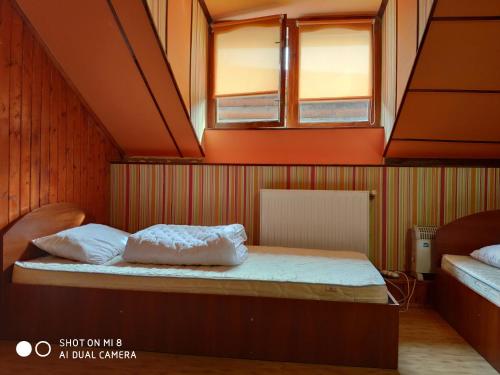 a small room with a bed with two windows at Hostel Vokzal in Mukacheve