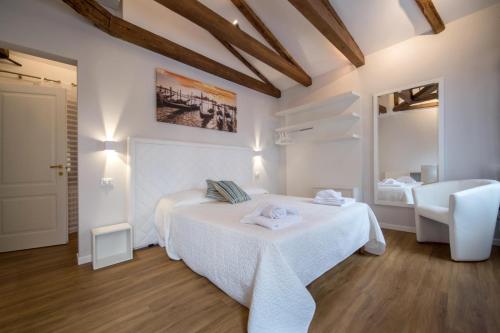a white bedroom with a bed and a chair at Corte Nova in Venice