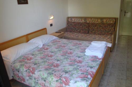 a bedroom with a bed with a floral bedspread at Hotel Vela Azzurra in Rimini