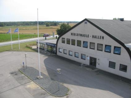 un grand bâtiment blanc avec un panneau sur son côté dans l'établissement Herlufmagle Hallen, à Herlufmagle