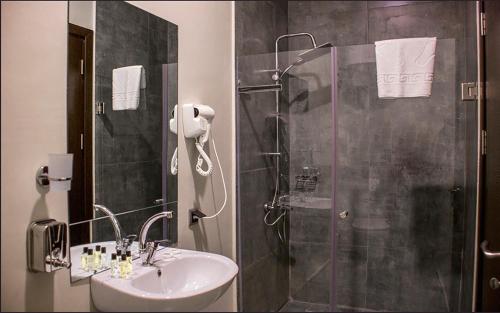 uma casa de banho com um chuveiro e um lavatório. em Legend Business Hotel Batumi em Batumi