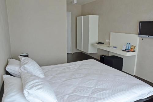 a white bed in a room with a desk at Fletcher Hotel - Restaurant Elzenduin in Ter Heijde