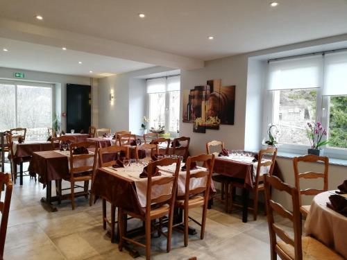 a dining room with tables and chairs and windows at Logis Hôtel Restaurant Les Cévennes in Saint-Cirgues-en-Montagne