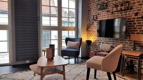 ein Wohnzimmer mit Stühlen und einem TV an einer Backsteinwand in der Unterkunft Little Suite CLEM in Lille