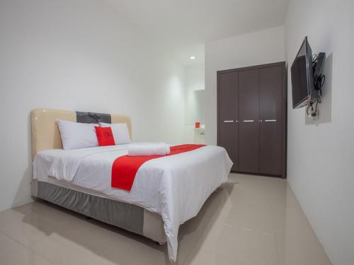a bedroom with a large bed and a television at RedDoorz @ Kertajaya Surabaya in Surabaya