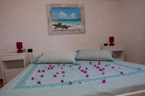 a bed with pink flowers on top of it at Club Esse Cala Bitta in Baja Sardinia