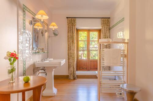 ein Bad mit einem Waschbecken und einem Spiegel in der Unterkunft Le Grand Hôtel in Moltig les Bains