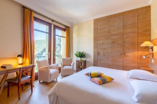 a bedroom with a bed and a desk and a window at Le Grand Hôtel in Molitg les Bains