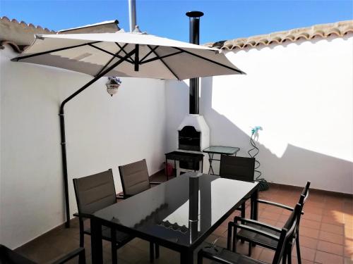 Casa Rural La Dehesa في La Mata: طاولة وكراسي مع مظلة على الفناء