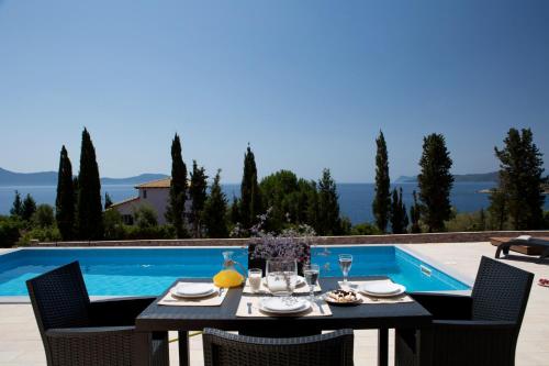 a dining table and chairs next to a swimming pool at Nema Villas in Meganisi