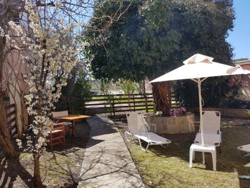 
a patio area with a table, chairs, and umbrella at CorfuGrace in Sidari
