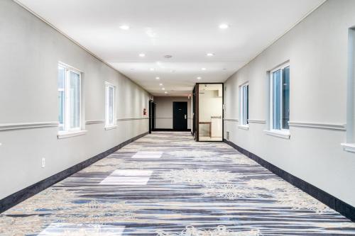 an empty hallway with windows and a carpeted floor at Alexis Hotel & Banquets Dallas Park Central Galleria in Dallas