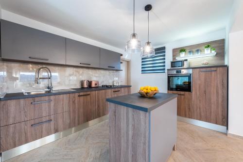 a kitchen with wooden cabinets and a counter with a bowl of fruit at Villa Paulina in Mlini