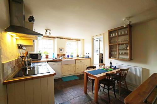 a kitchen with a table and a dining room at Yew Tree Cottage in Bath