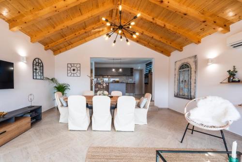 a dining room with white chairs and a wooden ceiling at Villa Paulina in Mlini