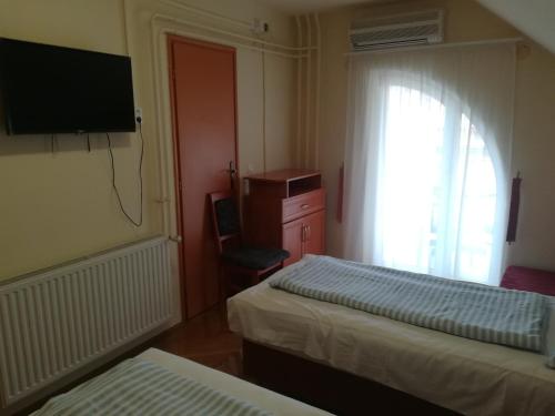 une chambre avec deux lits, une télévision et une fenêtre dans l'établissement Áldos Panzió, à Farád
