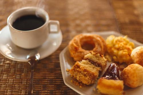 einen Teller Gebäck und eine Tasse Kaffee auf dem Tisch in der Unterkunft Pousada Le Sapê in São Lourenço