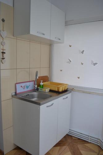 a kitchen with white cabinets and a sink at Relax Apartament in Constanţa