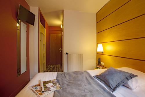 sypialnia z łóżkiem z drewnianym zagłówkiem w obiekcie Belambra City - Magendie w Paryżu