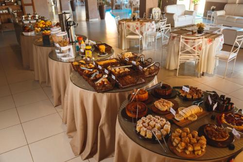 ein Buffet mit mehreren Tabletts mit Gebäck und anderen Speisen in der Unterkunft Pousada Le Sapê in São Lourenço
