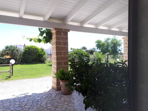 a porch with a brick pillar and plants on a patio at TENUTA ALMATELLUS in Torre Lapillo