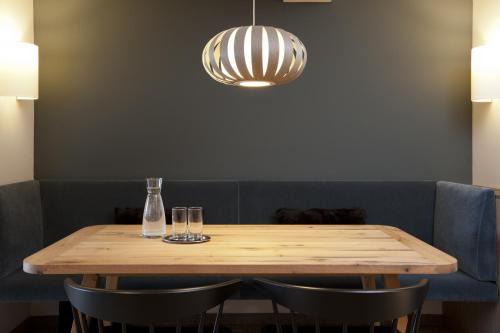 a wooden table with two glasses and a light fixture at Hotel Berghof in Lech am Arlberg