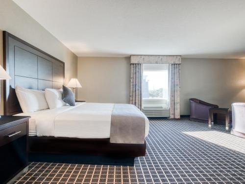 a hotel room with a large bed and a window at Alexis Hotel & Banquets Dallas Park Central Galleria in Dallas