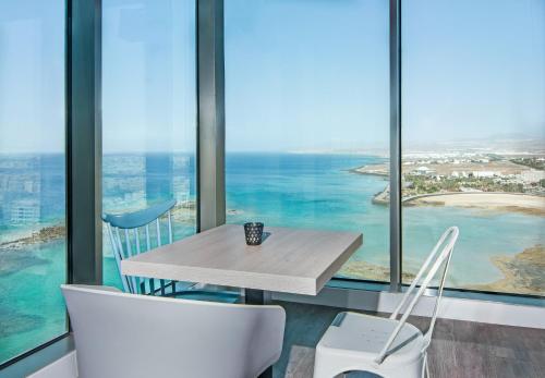 a table and two chairs in a room with windows at Arrecife Gran Hotel & Spa in Arrecife