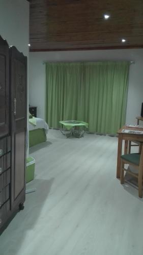 um quarto com uma mesa e uma cortina verde em Guest Lodge on the Edge em Stormsrivier