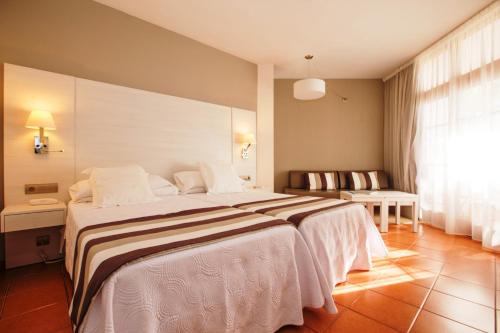 a hotel room with a large bed with white sheets at Hotel Tres Torres in Santa Eularia des Riu