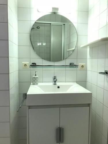 Baño blanco con lavabo y espejo en Koksijde App Zeelaan B3, en Koksijde