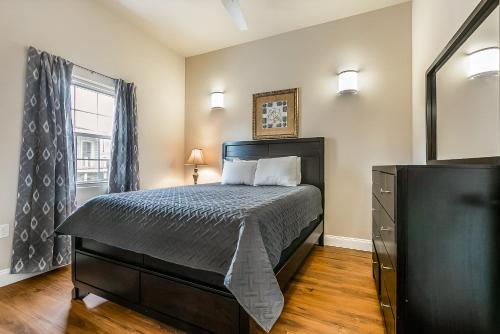 een slaapkamer met een bed, een dressoir en een raam bij Modern 5BR Condo in NOLA in New Orleans