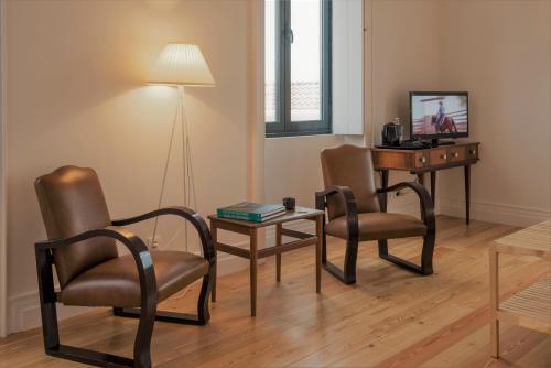 a living room with two chairs and a table and a desk at Herdade do Ananás in Ponta Delgada
