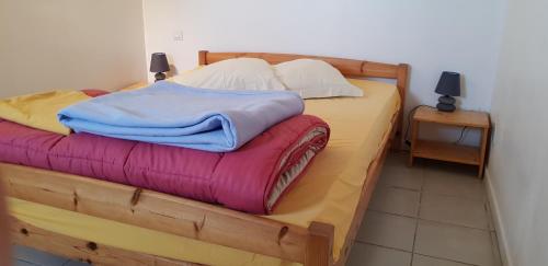 - une chambre avec un lit en bois et des couvertures colorées dans l'établissement Mas des cypres, à Saintes-Maries-de-la-Mer