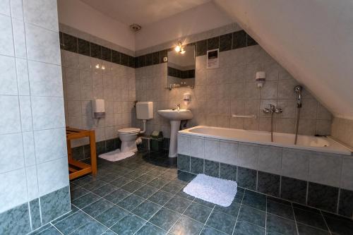 a bathroom with a tub and a toilet and a sink at Il Gallo Nero - Fekete Kakas Étterem és Panzió in Szombathely