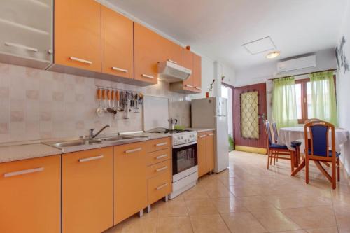 a kitchen with orange cabinets and a table and chairs at Apartments Nadia Sokolić in Nerezine